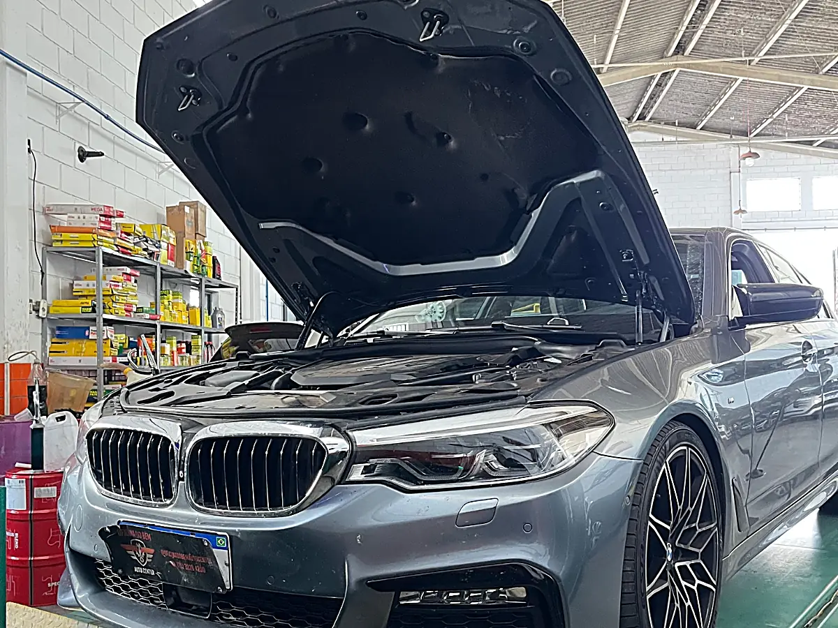 BMW com capô aberto sobre a rampa do elevador da Oficina do Bem